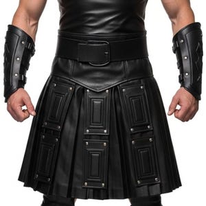 May include: Black leather kilt with rectangular panels and silver rivets. The kilt has pleats and is paired with a wide belt and matching arm cuffs. The cuffs have buckle closures and silver rivets.