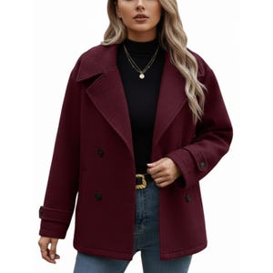 May include: A burgundy double-breasted coat with a notched collar and long sleeves. The coat features black buttons and a gold buckle belt. The coat is made of a textured fabric.