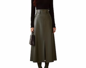 Può includere: Un top nero a maniche lunghe abbinato a una gonna in ecopelle verde oliva a vita alta. La gonna presenta uno spacco frontale e dettagli con bottoni. Una piccola borsa marrone scuro e stivali abbinati completano l'outfit.