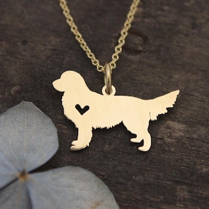May include: A gold-toned necklace featuring a pendant shaped like the silhouette of a dog in a standing position. The dog pendant includes a small, heart-shaped cutout located on the chest area and is suspended from a delicate gold-toned chain.