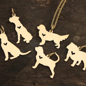 May include: Five gold-toned metal dog-shaped pendants, each featuring a small heart-shaped cutout on the chest area. One pendant is attached to a delicate gold-toned chain necklace, while the other four are individual charms with jump rings.