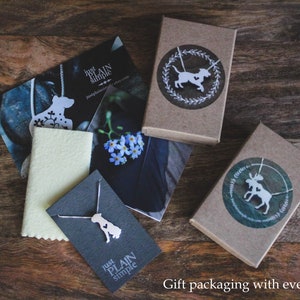 May include: Three gift boxes with brown paper wrapping and white silhouette designs of a dog, a moose, and a dog on a necklace. The boxes are on a wooden surface. The text "Just Plain Simple" is on two of the boxes.