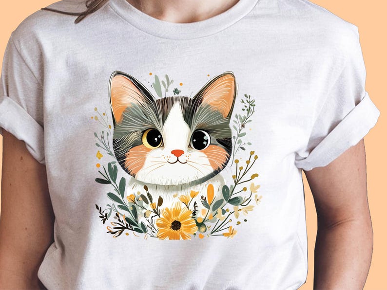 May include: A light gray t-shirt featuring a cute cat illustration. The cat has big eyes, a white face, and is surrounded by flowers and greenery. The cat's ears are orange and gray. The shirt is made of a soft material.