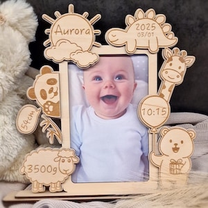 Op de afbeelding: Houten fotolijst met een babyfoto en gegraveerde details, waaronder de naam van de baby "Aurora", de geboortedatum "2025 03/01", de tijd "10:15", het gewicht "3500g" en de lengte "54cm". De lijst is versierd met schattige dierillustraties, waaronder een panda, een giraffe, een dinosaurus, een schaap en een beer.