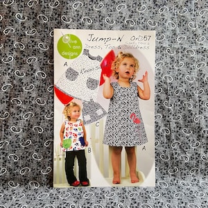 May include: A sewing pattern for a dress, top, and doll dress. The pattern is called "Jump-N" and the number is OAD57. The pattern is for sizes 1 through 6. The pattern is shown on a white background with a red balloon and two children wearing the garments.