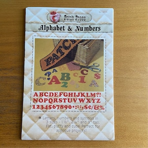 Może przedstawiać: Drukowany arkusz wzorów do aplikacji z alfabetem, liczbami i symbolami w trzech rozmiarach: 3,8 cm, 5,7 cm i 7,6 cm wysokości. Arkusz nosi tytuł "Patch Press Alphabet & Numbers" i zawiera tekst "Letters, numbers and symbols in 3 sizes - 1 1/2", 2 1/4" and 3" tall. Fat, puffy and cute! Perfect for applique projects!"
