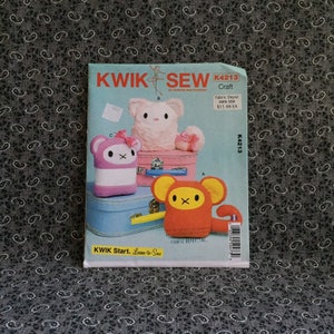 May include: A sewing pattern for making three plush toys: a pink bunny, a purple and white panda, and an orange monkey. The pattern is called "KWIK SEW" and the pattern number is K4213. The pattern is from Fabric Depot and costs £11.99.