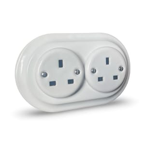 May include: A white double electrical socket with two sockets. Each socket has three rectangular holes. The oval-shaped faceplate is glossy and secured with small screws. A common UK electrical fitting.