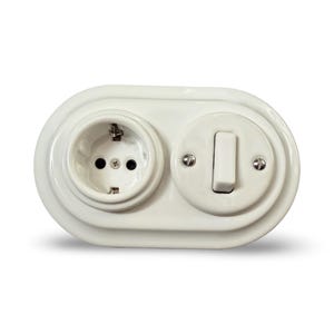 May include: A white electrical outlet and light switch combo. The outlet has three holes and the switch is a simple on/off toggle. The faceplate is oval-shaped and has a glossy finish. The design is a classic, vintage style.
