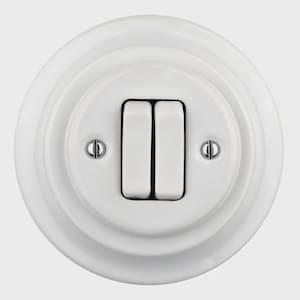 Könnte beinhalten: Ein weißer Doppelschalter mit rundem, abgestuftem Design. Der Schalter hat zwei rechteckige, weiße Kippschalter und zwei kleine Schrauben auf beiden Seiten. Das Design ist sauber und minimalistisch.