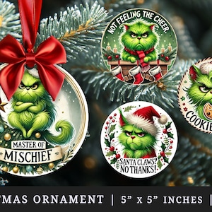 Op de afbeelding: Kerstversieringen met een groene cartoonfiguur met een boze uitdrukking. Eén ornament heeft de tekst "MASTER OF MISCHIEF". Andere ornamenten hebben de zinnen "NOT FEELING THE CHEER", "SANTA CLAWS? NO THANKS!" en "COOKIE THIEF".