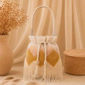 May include: A bucket-style handbag covered in cream, light pink, and mustard yellow beads arranged in a diamond pattern. The bag features a single top handle, a drawstring closure with two beaded tassels, and long fringe trim along the bottom edge.