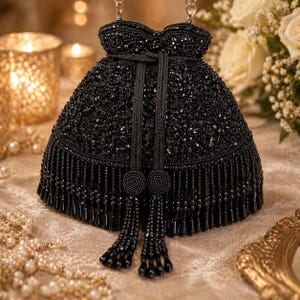 May include: A black beaded handbag with a drawstring closure and a chain strap. The bag features intricate beadwork and a fringe along the bottom edge. Two beaded tassels hang from the front of the bag.