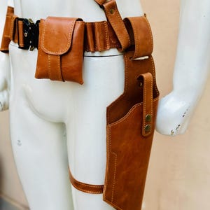 Peut inclure: Un syst&egrave;me de ceinture et d'&eacute;tui en cuir marron avec une bandouli&egrave;re, des pochettes de ceinture et une sangle de jambe. L'&eacute;tui est con&ccedil;u pour contenir une arme &agrave; feu. Le cuir est de couleur marron moyen et chaud.