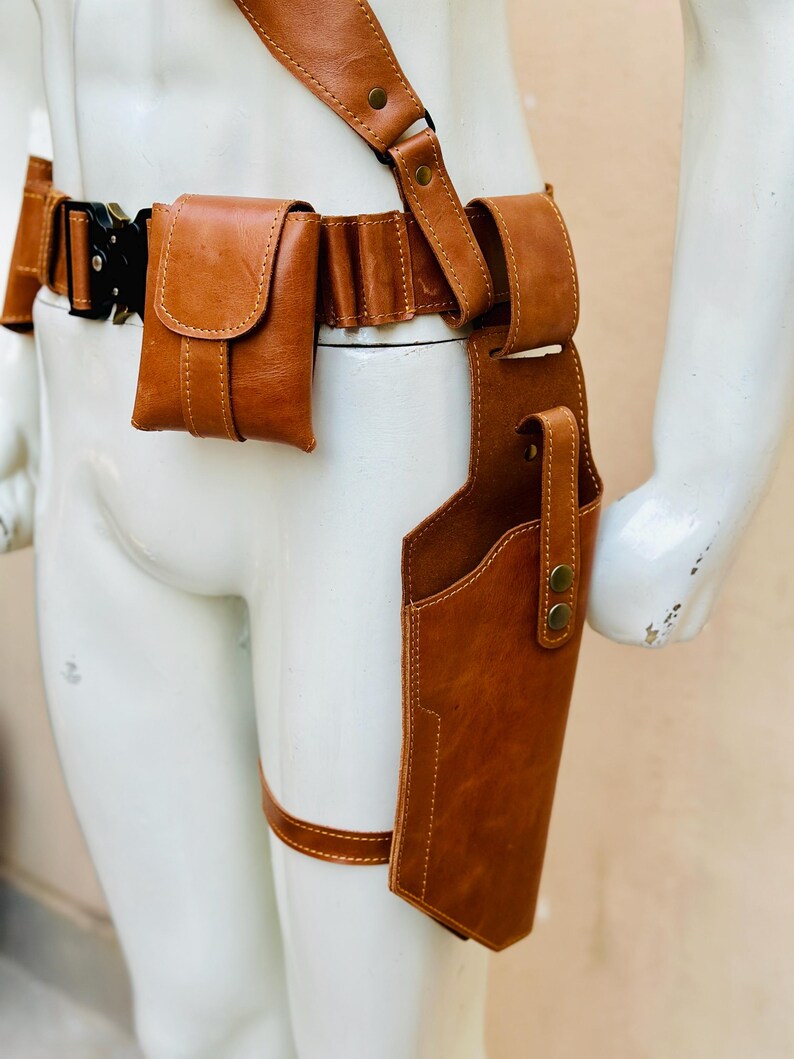 Peut inclure: Un syst&egrave;me de ceinture et d'&eacute;tui en cuir marron avec une bandouli&egrave;re, des pochettes de ceinture et une sangle de jambe. L'&eacute;tui est con&ccedil;u pour contenir une arme &agrave; feu. Le cuir est de couleur marron moyen et chaud.