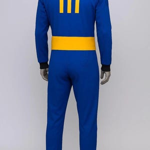 Op de afbeelding: Blauw jumpsuit met een gele tailleband en het nummer 111 in het geel op de rug gedrukt. De jumpsuit heeft lange mouwen met zwarte manchetten. Een cosplay kostuum.