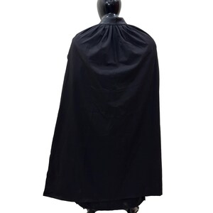 May include: A black cape with a high collar and a gathered neckline. The cape is made of a smooth, flowing fabric.