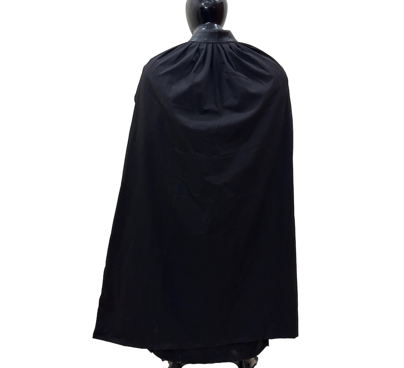 May include: A black cape with a high collar and a gathered neckline. The cape is made of a smooth, flowing fabric.