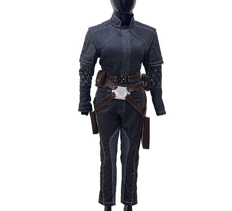 Puede incluir: Un mono azul oscuro con un cintur&oacute;n de cuero marr&oacute;n y una hebilla plateada. El mono tiene una cremallera y un cuello alto. El mono tiene bolsillos en los lados y en las piernas.