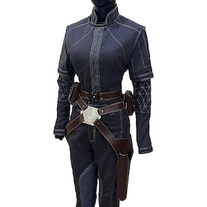 Puede incluir: Un mono azul oscuro con un cintur&oacute;n de cuero marr&oacute;n y una hebilla plateada. El mono tiene una cremallera y un cuello alto. El mono tiene un patr&oacute;n geom&eacute;trico en las mangas.