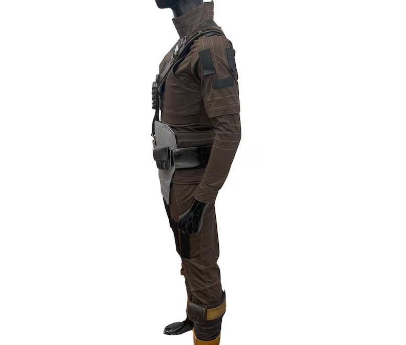 May include: A brown costume with a high collar, shoulder pads, and multiple pockets. The outfit includes a belt, a chest piece, and gloves. The boots have a brown and gold color scheme. The costume is displayed on a mannequin.