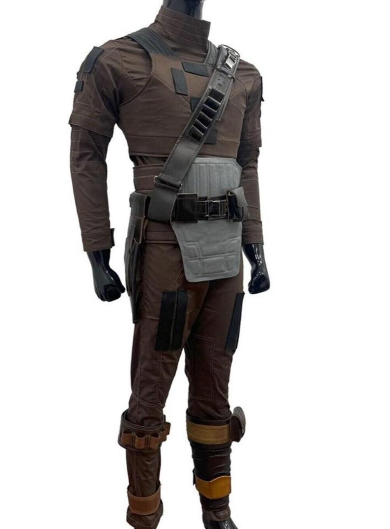 May include: A brown costume with a high collar, shoulder pads, and a utility belt. The outfit includes a chest piece, a shoulder strap with pouches, and matching pants. The boots have brown and tan accents. The mannequin is wearing black gloves.