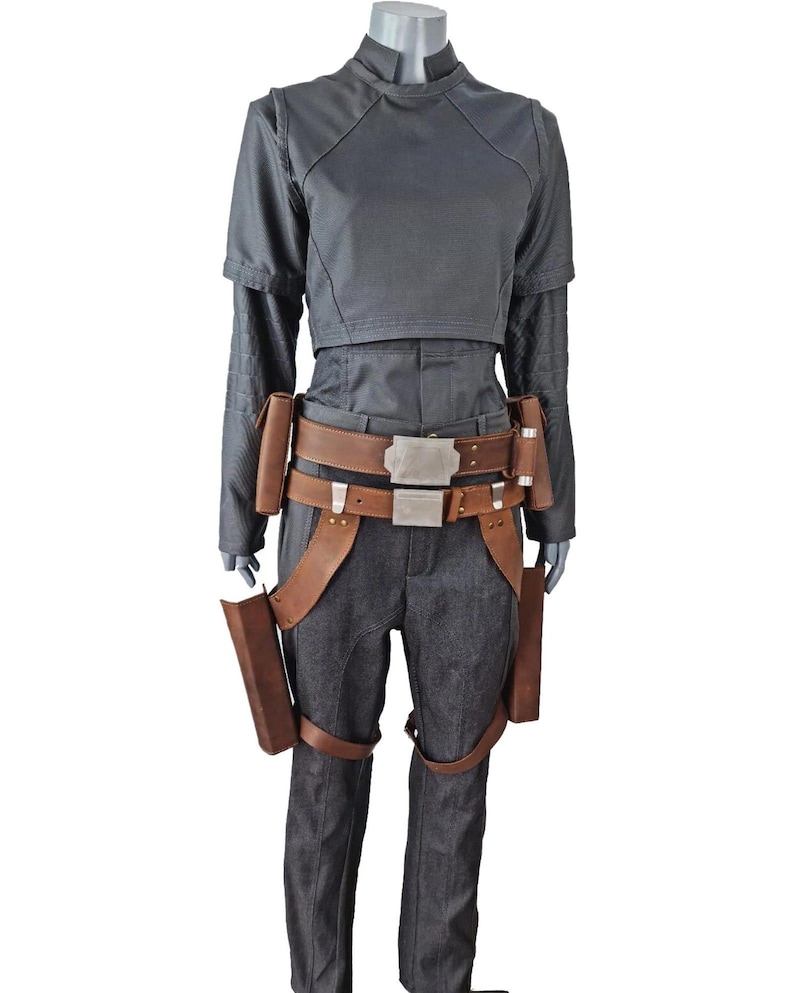May include: A dark grey costume featuring a mock neck top, long sleeves, and matching trousers. The costume includes a brown leather belt with a silver buckle and brown leather holsters. Ideal for cosplay or costume events.