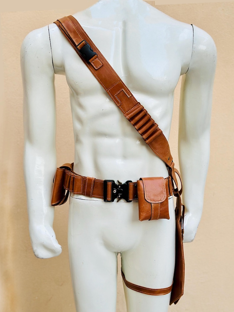 Peut inclure: Ensemble de ceinture utilitaire et bandouli&egrave;re en cuir marron. La ceinture est dot&eacute;e d'une boucle noire et de plusieurs pochettes. La bandouli&egrave;re a une boucle noire et une s&eacute;rie de boucles. Une sangle de jambe est &eacute;galement incluse.