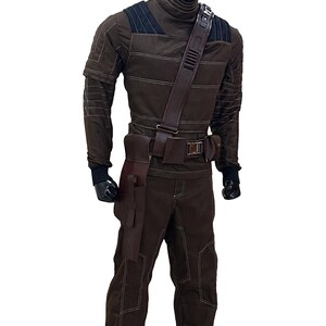 Pu&ograve; includere: Costume marrone con cuciture bianche, con collo alto, dettagli sulle spalle e cintura multiuso con tasche. L'outfit include pantaloni abbinati e una fondina. Il manichino indossa guanti neri.
