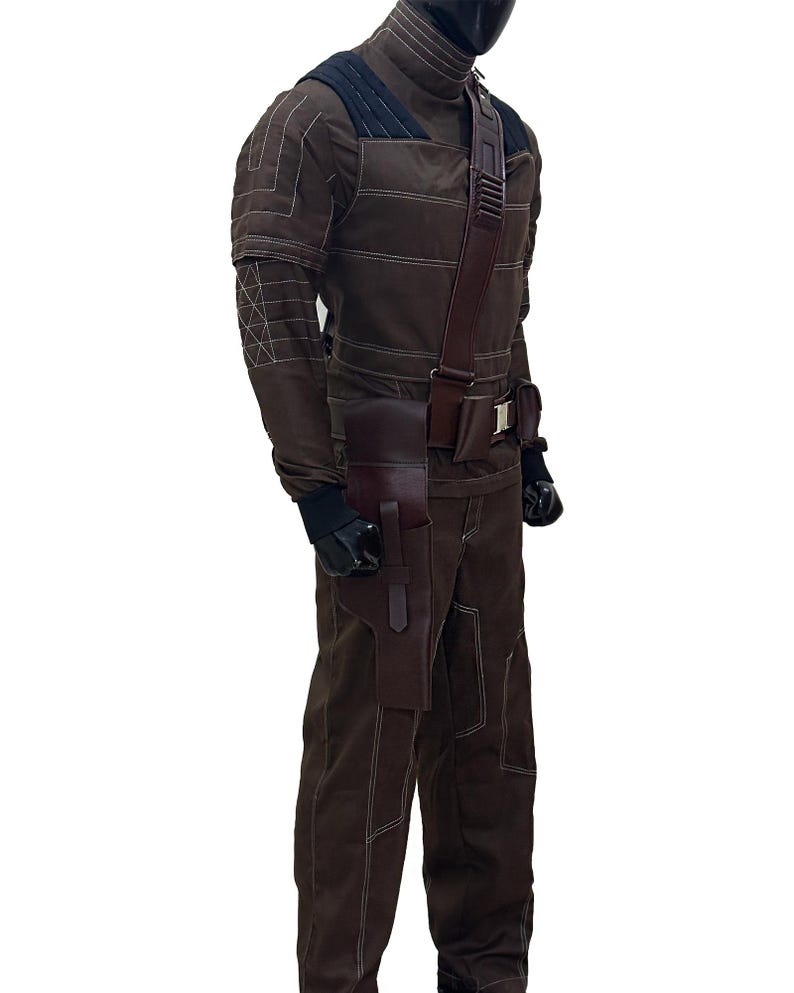 Pu&ograve; includere: Tuta marrone con cuciture bianche, collo alto e tracolla e fondina in pelle marrone scuro. L'outfit include guanti neri e una copertura per il viso nera. Il design suggerisce un tema tattico o futuristico.