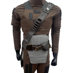 May include: A brown and gray costume with a tactical vest, shoulder strap, and belt. The costume includes a long-sleeved shirt, pants, and a chest plate. The shoulder strap has multiple loops. The mannequin is wearing black gloves.