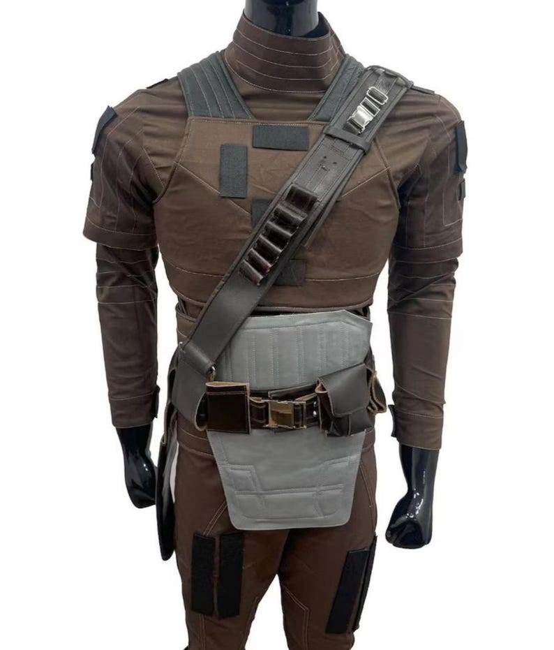 May include: A brown and gray costume with a tactical vest, shoulder strap, and belt. The costume includes a long-sleeved shirt, pants, and a chest plate. The shoulder strap has multiple loops. The mannequin is wearing black gloves.