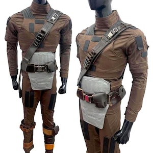 May include: Brown costume with a high collar, shoulder strap, and utility belt. The outfit includes a chest plate, leg armor, and gloves. The costume is displayed on a mannequin.