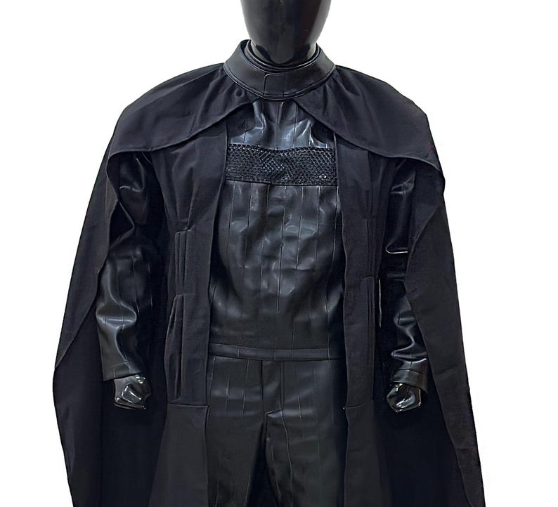 May include: A black hooded robe with a long cape. The robe has a high collar and a zipper closure. The fabric is smooth and has a slight sheen.