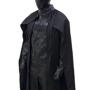May include: A black costume with a long black cape. The costume has a high collar and a textured design on the chest.