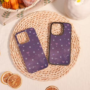 Peut inclure: Deux coques de téléphone avec un motif de ciel étoilé violet et rose. Les coques ont un motif de petites étoiles et de cœurs.