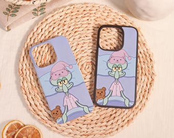 May include: Two light purple phone cases featuring a graphic illustration of Squidward Tentacles wearing a pink nightcap and pyjamas while lying in bed with a small brown teddy bear. The cases have a cutout for the camera lens.
