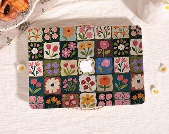 May include: A laptop hard shell case featuring a grid pattern of square tiles, each displaying a unique hand-painted style floral illustration in various colours including pink, orange, yellow, white, and green, with a central cutout for an Apple logo.