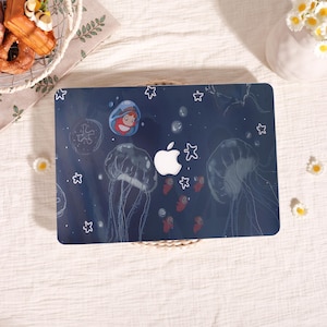 Peut inclure: Une coque d'ordinateur portable bleu foncé avec un motif sous-marin. On y voit des méduses, des bulles et des étoiles de mer. Un personnage de dessin animé et le logo Apple sont également présents. Design fantaisiste et coloré.