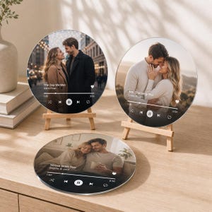 May include: Three circular glass plaques featuring custom photo prints of couples, each designed to resemble a music player interface with song titles, artist names, and playback controls. Two plaques are displayed on small wooden easels.