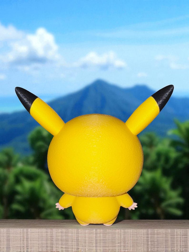 May include: A yellow Pikachu figure with black-tipped ears and small pink hands and feet. The figure is set against a backdrop of a mountain, blue sky, and green foliage. The figure is a popular character from the Pok&eacute;mon franchise.