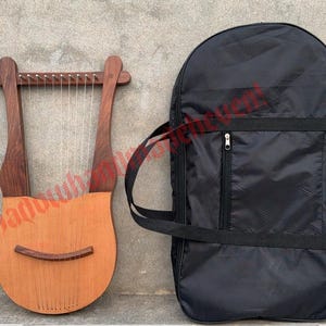 May include: A wooden lyre with strings and a carrying case. The lyre is brown and has a natural wood finish. The carrying case is black and has a zipper.