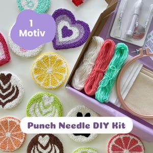 Könnte beinhalten: Ein Punch-Needle-DIY-Set mit einem hölzernen Stickrahmen, weißem Stoff, drei Garnsträngen in Weiß, Koralle und Minzgrün sowie einem Punch-Needle-Werkzeug, umgeben von verschiedenen fertigen Punch-Needle-Untersetzern mit Frucht- und Herzmotiven.
