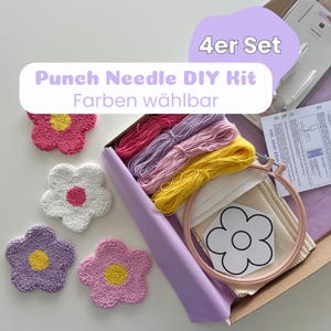Könnte beinhalten: Ein Punch-Needle-DIY-Set in einer Schachtel mit vier Garnbündeln in Pink, Lavendel, Hellrosa und Gelb, einem hölzernen Stickrahmen, einem Stück Stoff, einer Blumen-Mustervorlage und einer Anleitung. Vier fertige Blumen-Untersetzer sind enthalten.