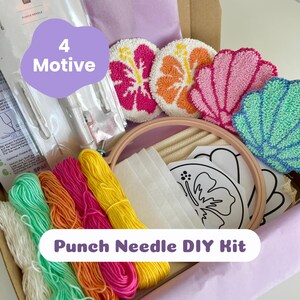 Könnte beinhalten: Ein Punch-Needle-DIY-Set mit einem hölzernen Stickrahmen, vier Garnsträngen in Weiß, Grün, Orange und Gelb, einem Punch-Needle-Werkzeug, Stoff, gedruckten Vorlagen sowie vier fertigen Punch-Needle-Untersetzern in Blumen- und Muschelformen.