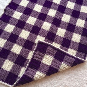 May include: Purple and white checkered crochet blanket with a soft, fuzzy texture.