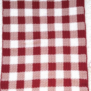 May include: A red and white gingham crochet blanket with a textured pattern.