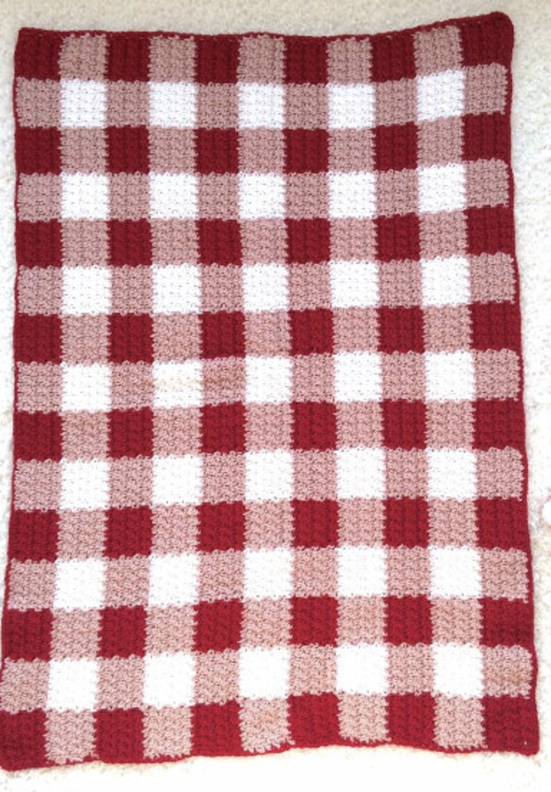May include: A red and white gingham crochet blanket with a textured pattern.