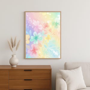 Könnte beinhalten: Ein gerahmter Aquarelldruck mit Blumen, der einen pastellfarbenen Regenbogenhintergrund und Blumen in Rosa, Gelb und Blau zeigt. Das Kunstwerk wird an einer weißen Wand über einem Holzschrank ausgestellt.