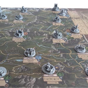Könnte beinhalten: Ein Brettspiel mit einer großen, detaillierten Karte mit verschiedenen Geländetypen und nummerierten Standorten. Zahlreiche kleine, graue, dreidimensionale Kunststoff-Miniaturstrukturen sind auf dem Spielbrett platziert.